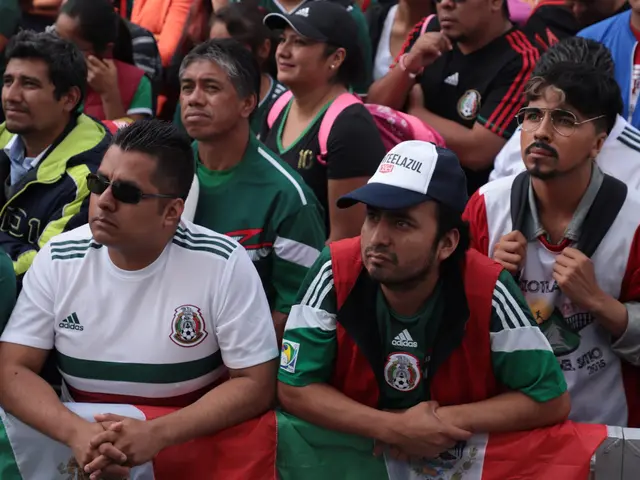 The image shows a group of Mexican fans sitting in the stands at a soccer game, some wearing...