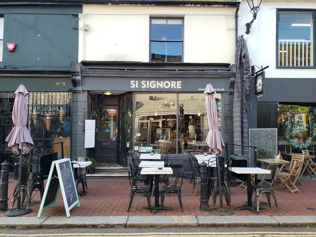 The image shows a restaurant, Si Signore, located on the corner of a street. There are tables and...