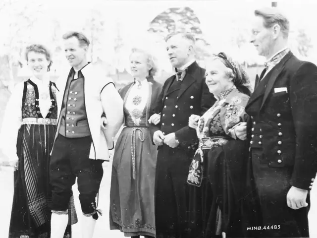 The image shows a group of people standing next to each other in black and white, smiling. In the...