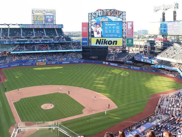 The image shows a baseball game being played in a stadium, with a group of people on the ground and...