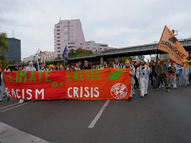 The image shows a group of people walking down a street, holding a banner that reads "Climate...