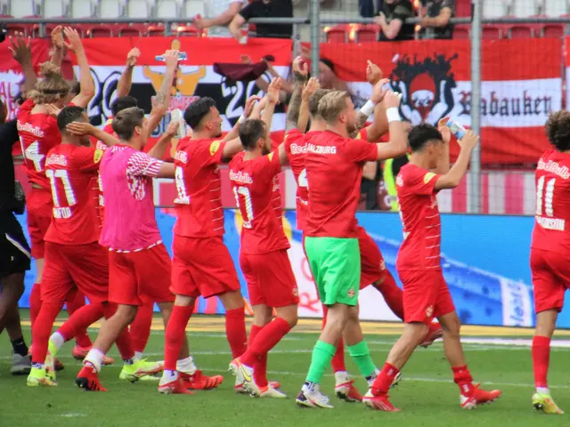 The image shows a group of soccer players celebrating a goal on a field. We can see the players...