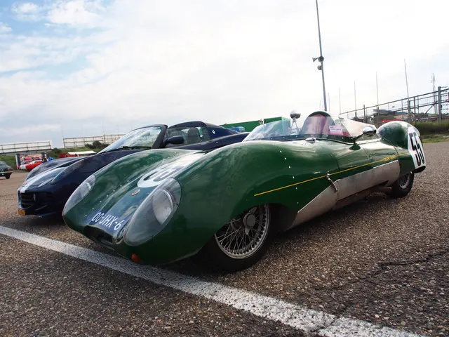 The image shows a group of cars parked next to each other on a race track, with a person sitting in...