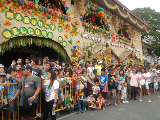 The image shows a large crowd of people standing in front of a building decorated with colorful...
