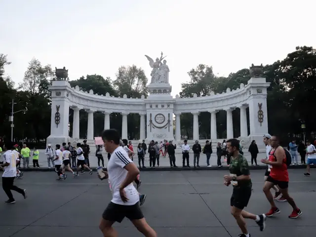 The image shows a group of people running in a marathon in front of a monument with pillars and...