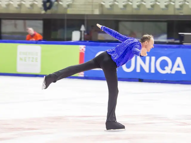 The image shows a man in a blue shirt and black pants skating on an ice rink, with a banner in the...