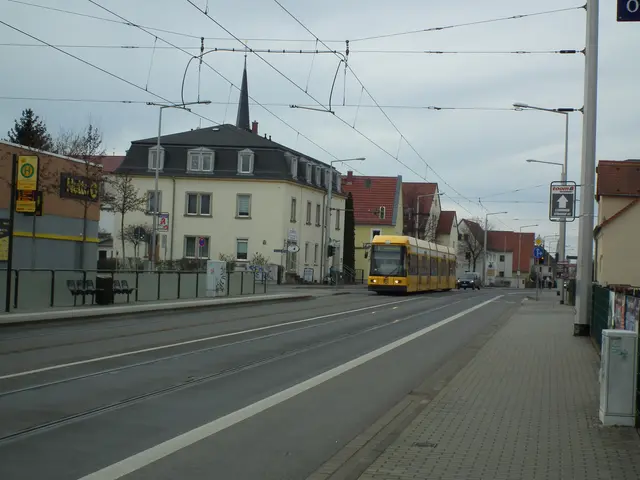 The image shows a yellow tram traveling down a street lined with tall buildings, street poles,...
