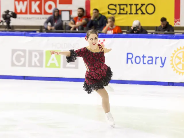 The image shows a woman in a red and black dress gracefully skating on an ice rink, surrounded by a...