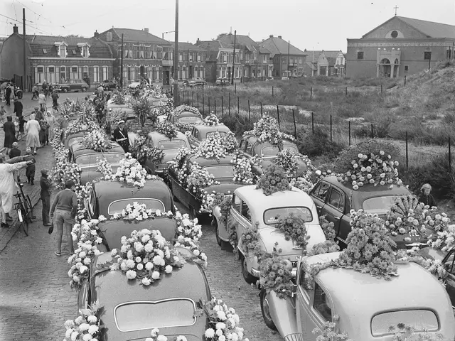 The image shows a black and white scene of a funeral procession with many cars adorned with flower...