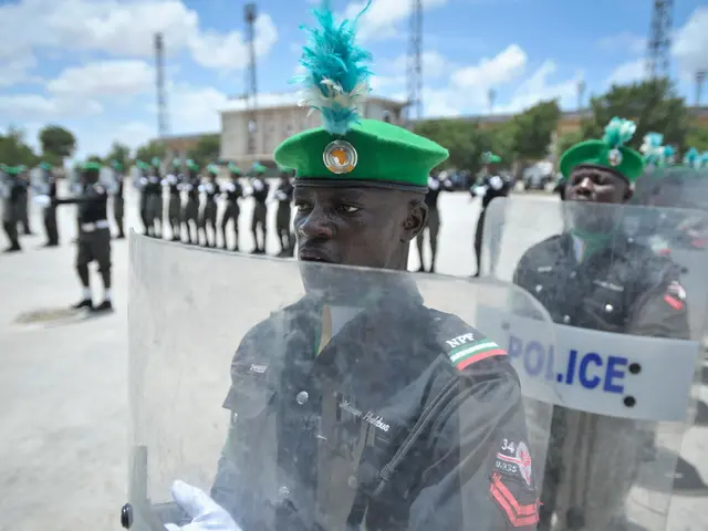 The image shows a group of Nigerian police officers standing in front of a line of people wearing...