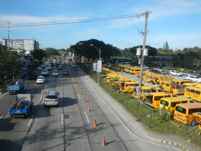 The image shows a busy street filled with lots of traffic, including cars, trucks, and buses. There...