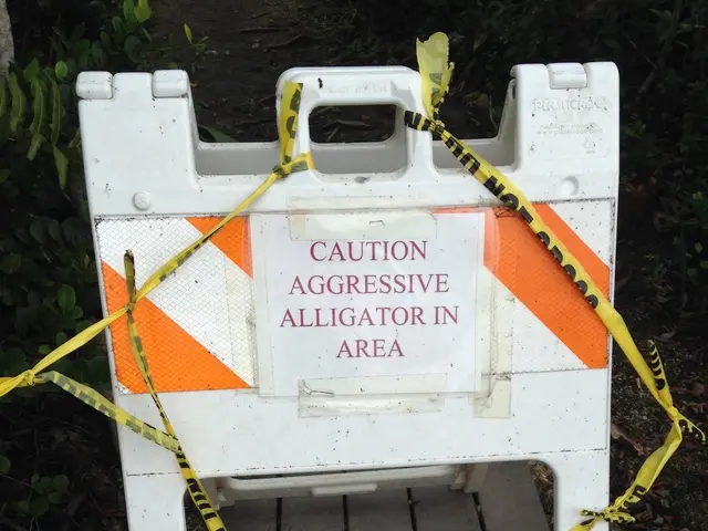 The image shows a white and orange caution sign sitting on the side of a road, with a caution tape...