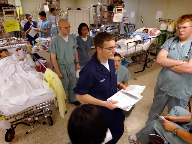 The image shows a group of people in scrubs standing around a hospital bed, with two people lying...