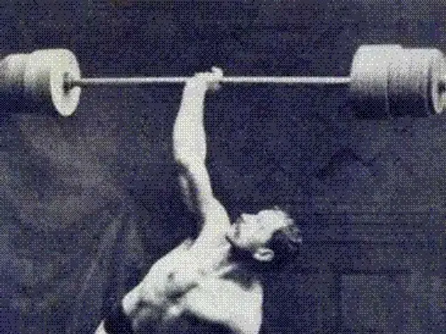 The image shows a man lifting a barbell in a weightlifting competition. He is standing upright with...