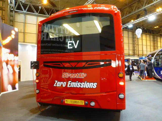 The image shows a red double decker bus parked inside of a building, surrounded by a group of...