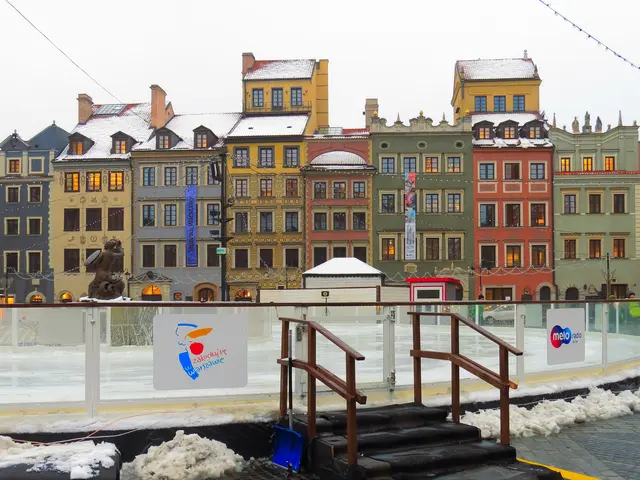 The image shows an ice skating rink in the middle of a city square surrounded by buildings with...