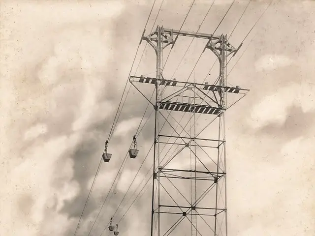 The image shows an old black and white photo of a high voltage power line with a cable car in the...