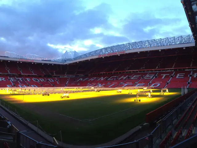 The image shows Old Trafford Stadium, home of Manchester United. It is a large stadium with a...