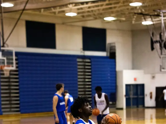 The image shows a woman in a blue and white uniform shooting a basketball on a court surrounded by...