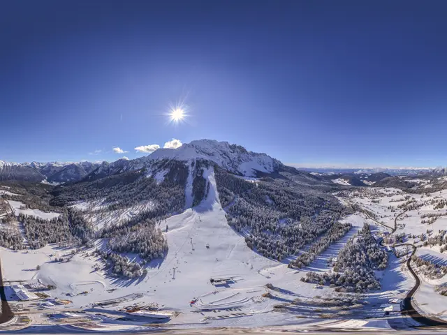 The image shows a panoramic view of a snowy mountain range with a ski slope in the foreground,...