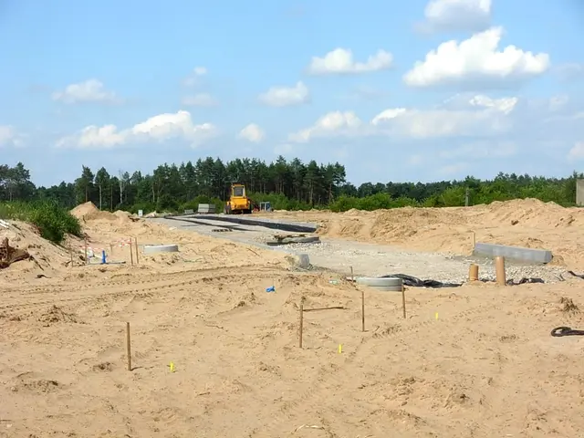 The image shows a construction site with a bulldozer in the middle of it, surrounded by sand,...