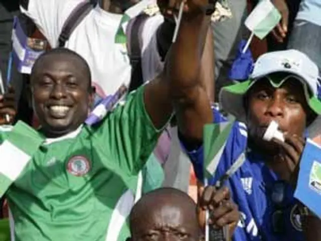 The image shows a group of Nigerian football fans celebrating their team's victory in the African...