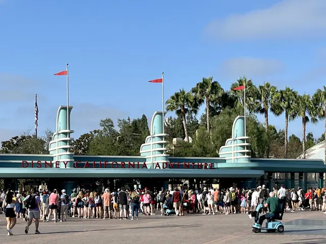 The image shows a group of people standing in front of the entrance to Disneyland California...