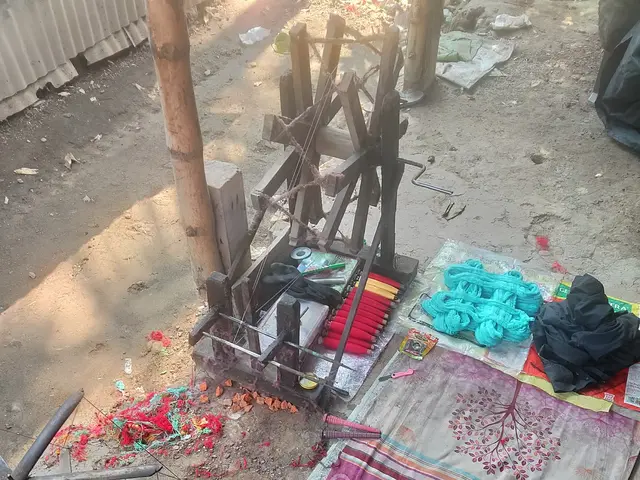 The image shows a wooden spinning wheel sitting on top of a dirt ground next to a pile of clothes,...