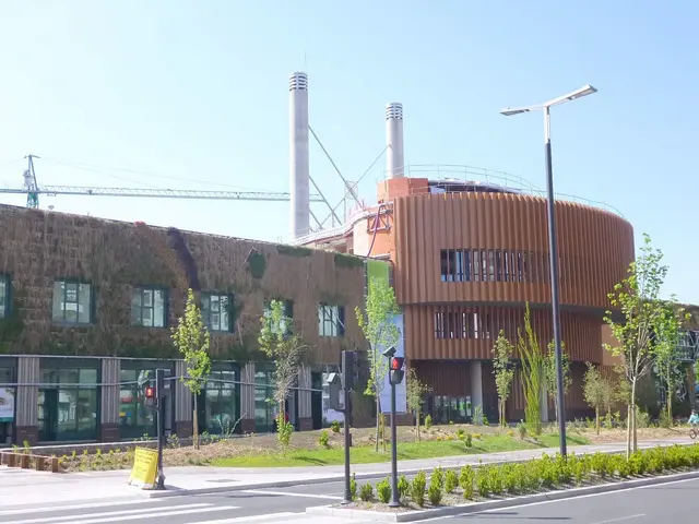 The image shows a large building with a green roof on the side of it, surrounded by trees, plants,...