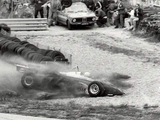 The image shows a black and white photo of a race car crashing into a pile of tires. There are...