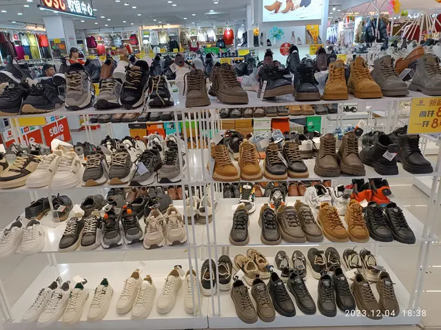 The image shows a store filled with lots of different types of shoes on racks, with price tags...