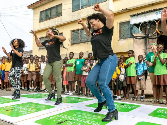 The image shows a group of people standing on top of a stage in front of a crowd. The people are...