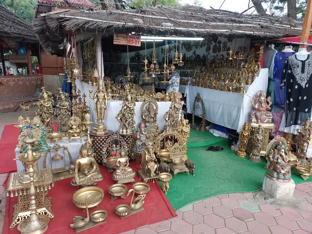 The image shows a market stall with a variety of brass items for sale, including idols, lamps, and...