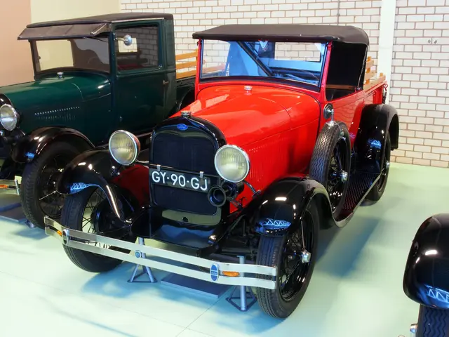 The image shows a group of old cars on display in a museum, with a wall in the background. The cars...