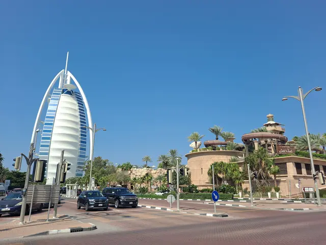 The image shows the iconic Burj Al Arab Hotel in Dubai, UAE. We can see vehicles on the road, light...