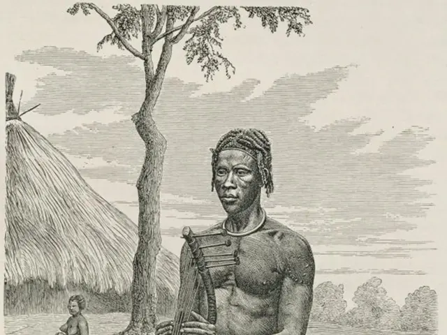 The image shows a man sitting on the ground playing a musical instrument, surrounded by a hut,...