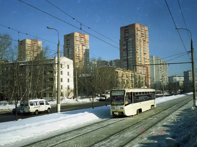 The image shows a city street with a tram on the tracks in the snow. There are vehicles on the...