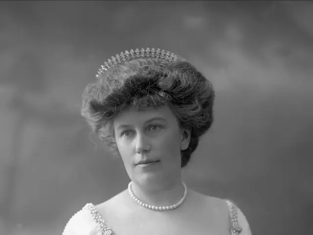 The image shows a black and white photo of a woman wearing a dress and a tiara. She has a regal air...