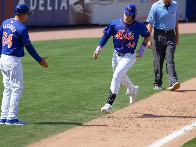 The image shows a baseball player running to first base during a game, with two people standing on...