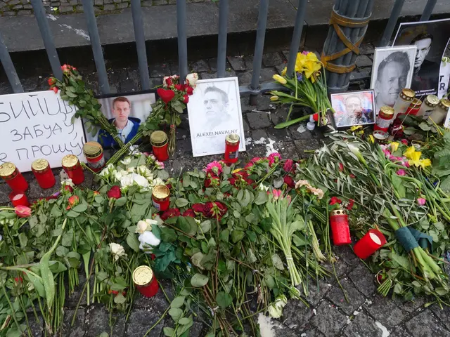 The image shows a memorial in Kiev, Ukraine, with flower bouquets, candles, photo frames, and other...