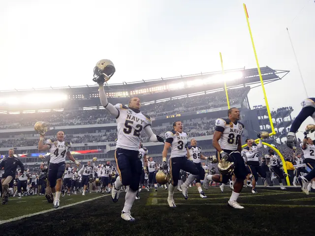 The image shows a group of people running on top of a football field, with some of them holding...