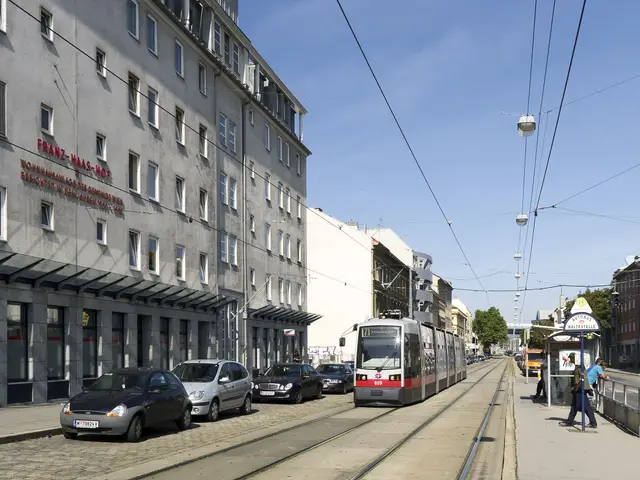 The image shows a city street with a tram on the tracks, cars parked on the side of the road,...