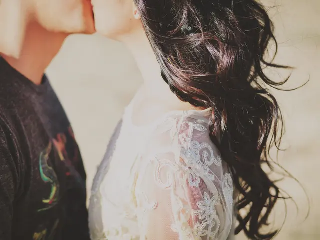 The image shows a man and woman passionately embracing and kissing in front of a beautiful sunset....