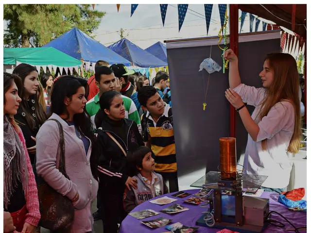 The image shows a group of people standing around a table with a sign that reads "Alumni Engagement...