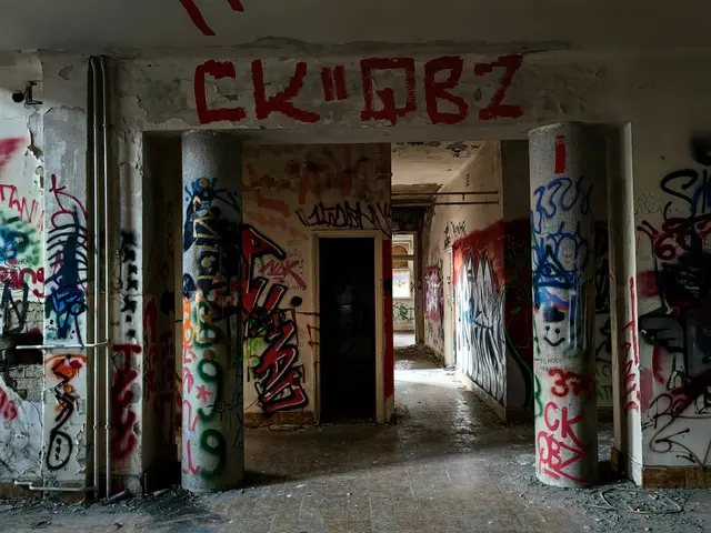 The image shows an abandoned building with graffiti on the walls and pillars. The floor is visible...