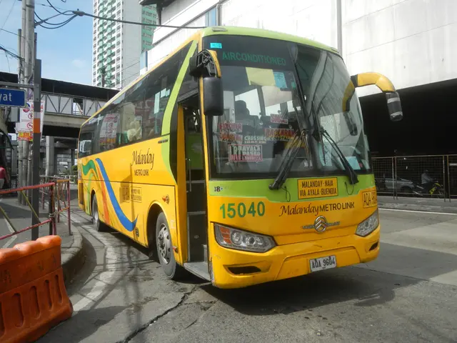 The image shows a yellow bus driving down a street lined with tall buildings. On the left side of...