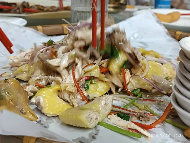 The image shows a table topped with plates of food and bowls of sauce, as well as chopsticks,...