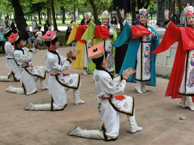 The image shows a group of people in traditional Chinese clothing performing a dance in front of a...