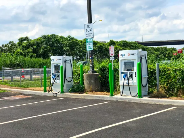 The image shows an electric vehicle charging station in the middle of a parking lot, surrounded by...