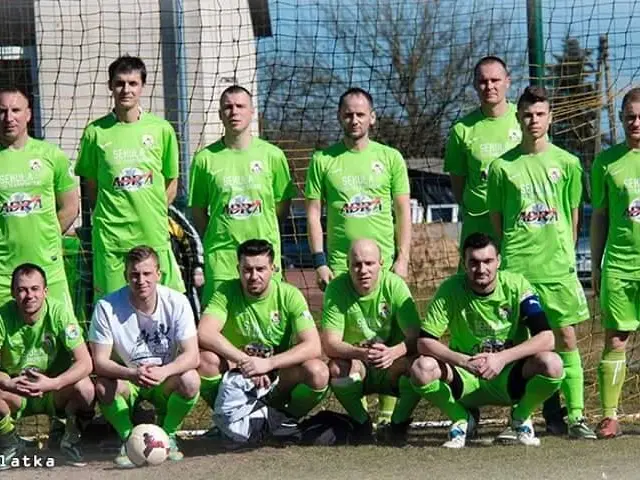 The image shows a group of men standing next to each other on a soccer field. They are wearing...
